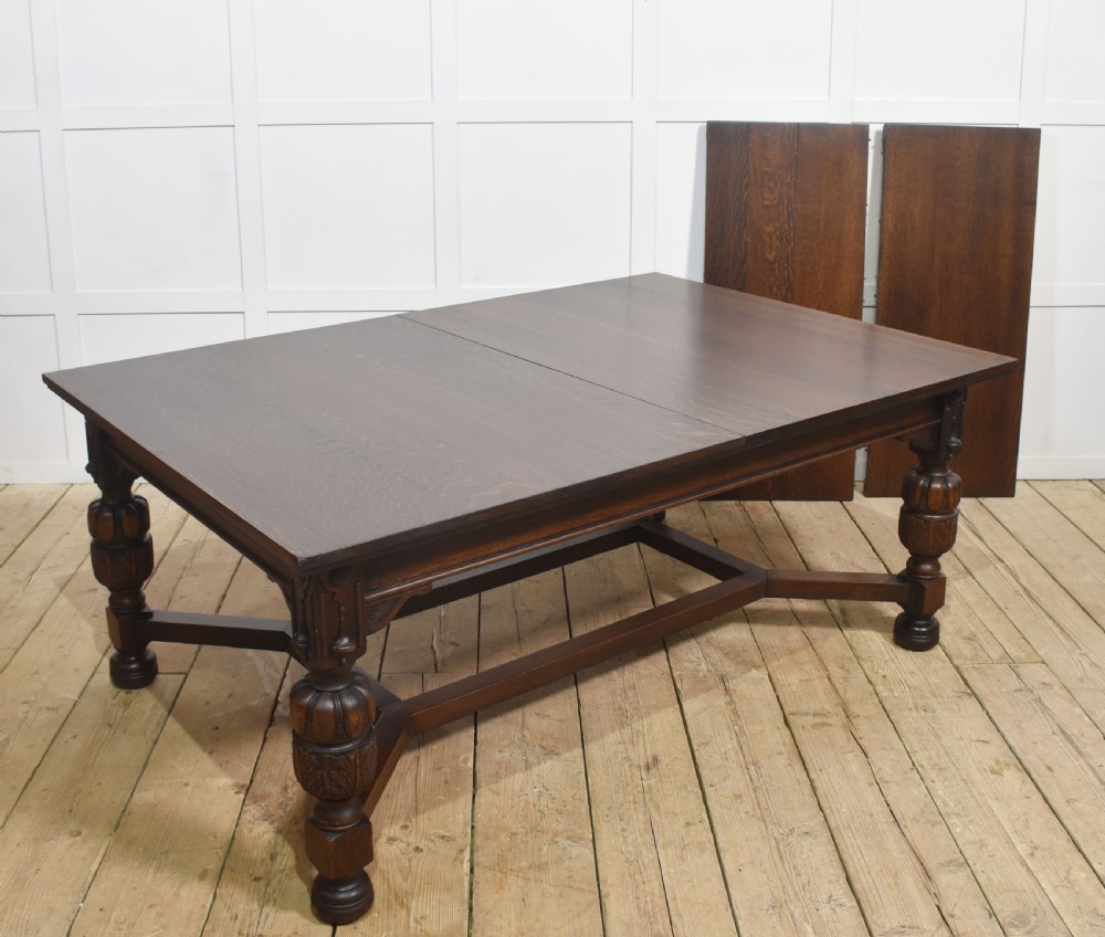 A dark oak extending dining table with carved bulbous legs and an H-stretcher base. View XIV