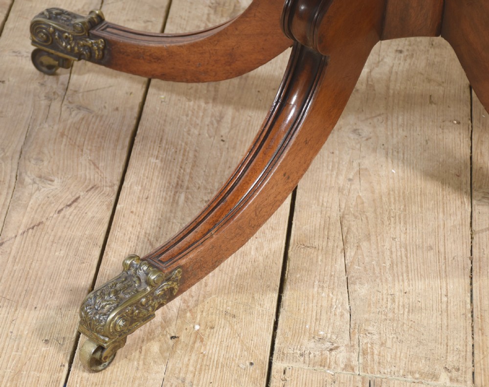 A Regency mahogany tilt-top breakfast table featuring a rectangular top with rounded corners, supported by a turned central pedestal and four splayed legs with brass paw castors. View IV