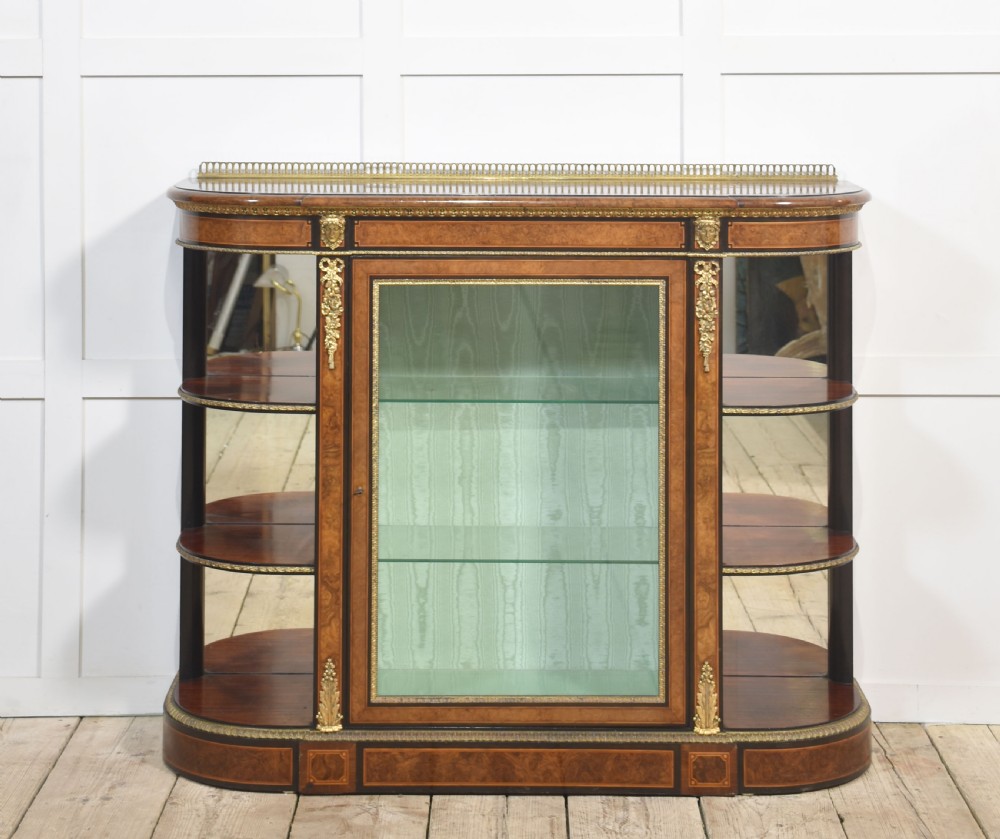 A 19th-century burr walnut credenza featuring a central glass door flanked by open curved shelves with mirrored backs and gilt-brass mounts.
