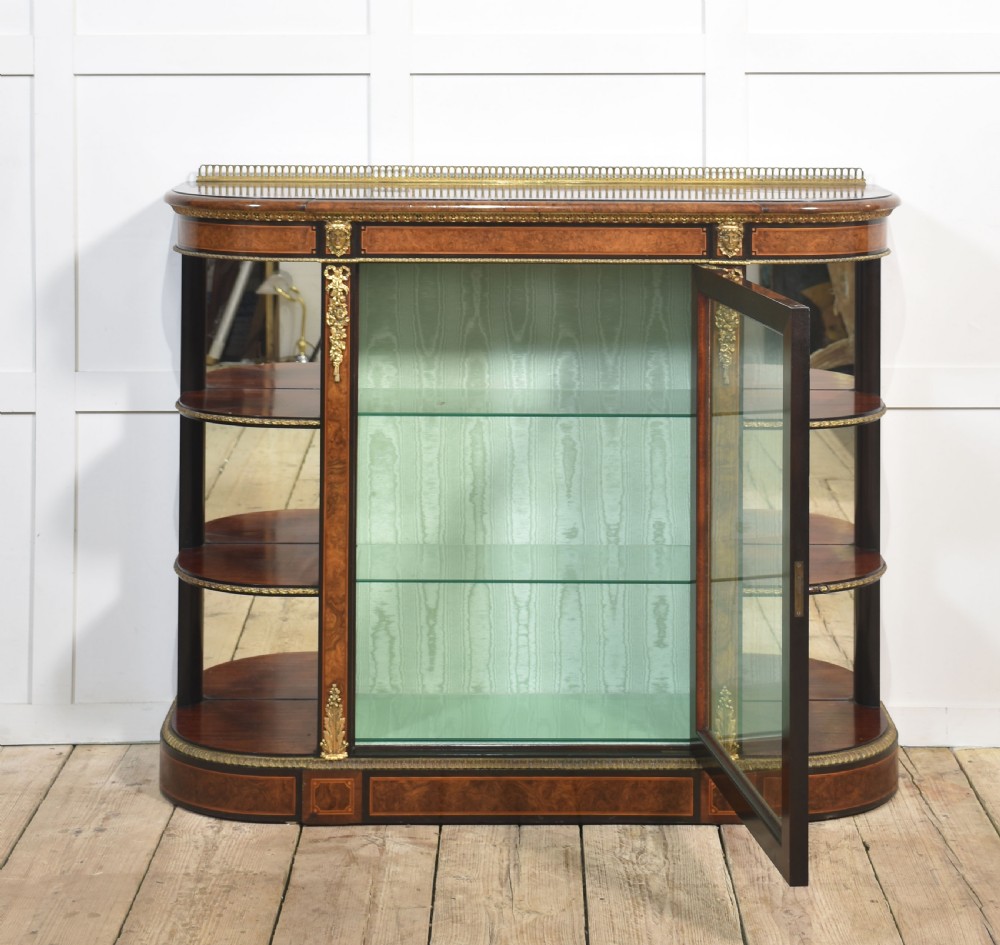 A 19th-century burr walnut credenza featuring a central glass door flanked by open curved shelves with mirrored backs and gilt-brass mounts. View III