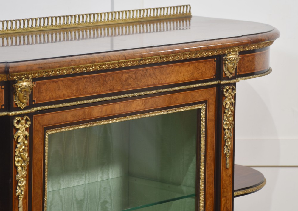 A 19th-century burr walnut credenza featuring a central glass door flanked by open curved shelves with mirrored backs and gilt-brass mounts. View XI