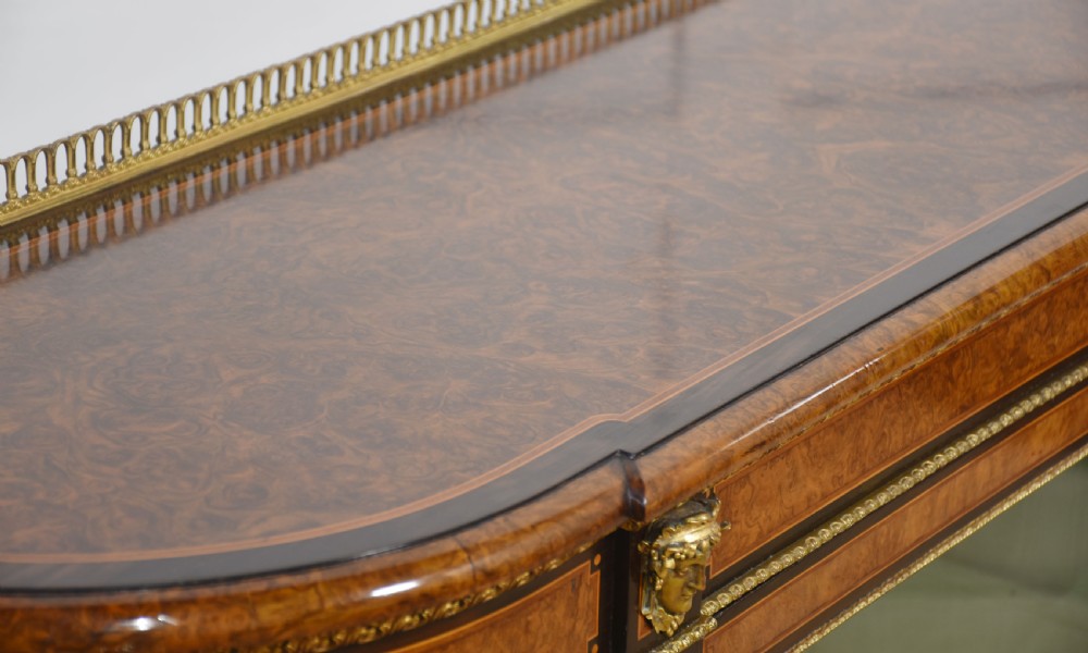 A 19th-century burr walnut credenza featuring a central glass door flanked by open curved shelves with mirrored backs and gilt-brass mounts. View XIII