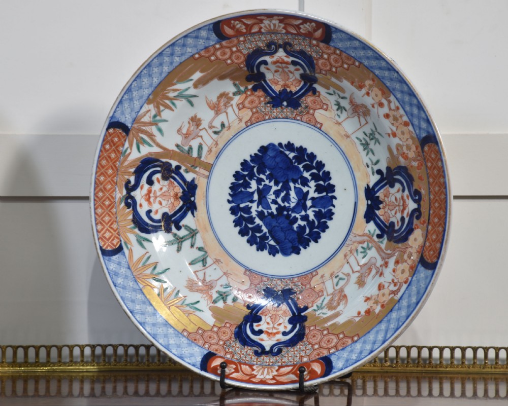 A pair of round Japanese Imari porcelain plates decorated with hand-painted cobalt blue, rust red, and gilded floral motifs. View II