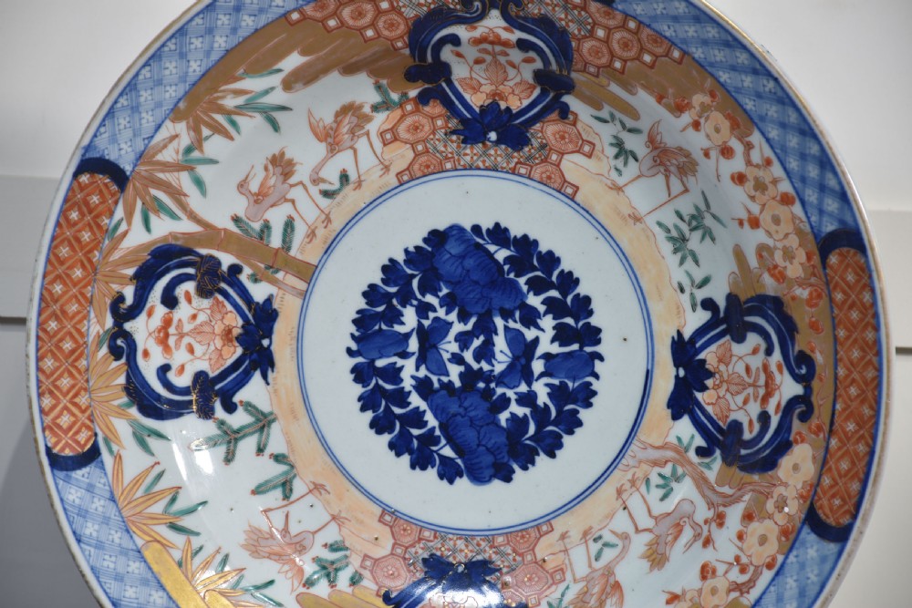 A pair of round Japanese Imari porcelain plates decorated with hand-painted cobalt blue, rust red, and gilded floral motifs. View V