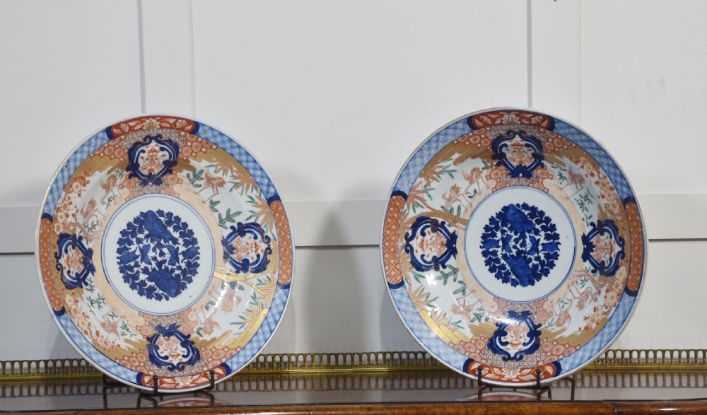 A pair of round Japanese Imari porcelain plates decorated with hand-painted cobalt blue, rust red, and gilded floral motifs. View VII