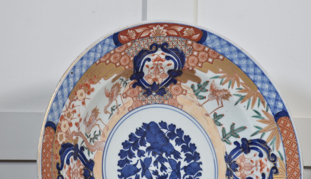 A pair of round Japanese Imari porcelain plates decorated with hand-painted cobalt blue, rust red, and gilded floral motifs. View VIII