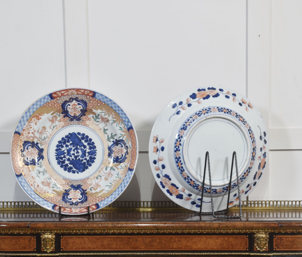 A pair of round Japanese Imari porcelain plates decorated with hand-painted cobalt blue, rust red, and gilded floral motifs. View IX