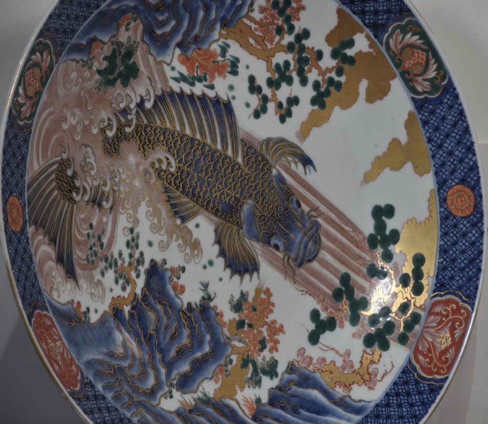 A circular Japanese Imari porcelain charger decorated with a blue and gold carp leaping up a waterfall amidst pine trees and geometric border motifs. View IV
