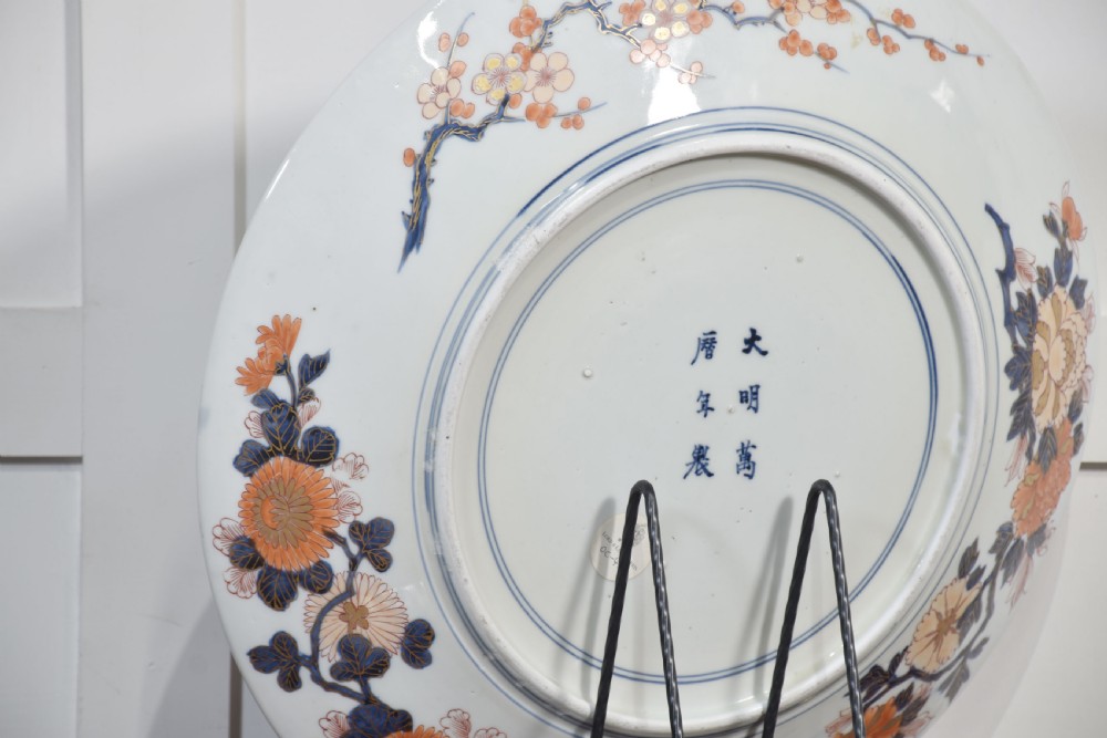 A circular Japanese Imari porcelain charger decorated with a blue and gold carp leaping up a waterfall amidst pine trees and geometric border motifs. View VII