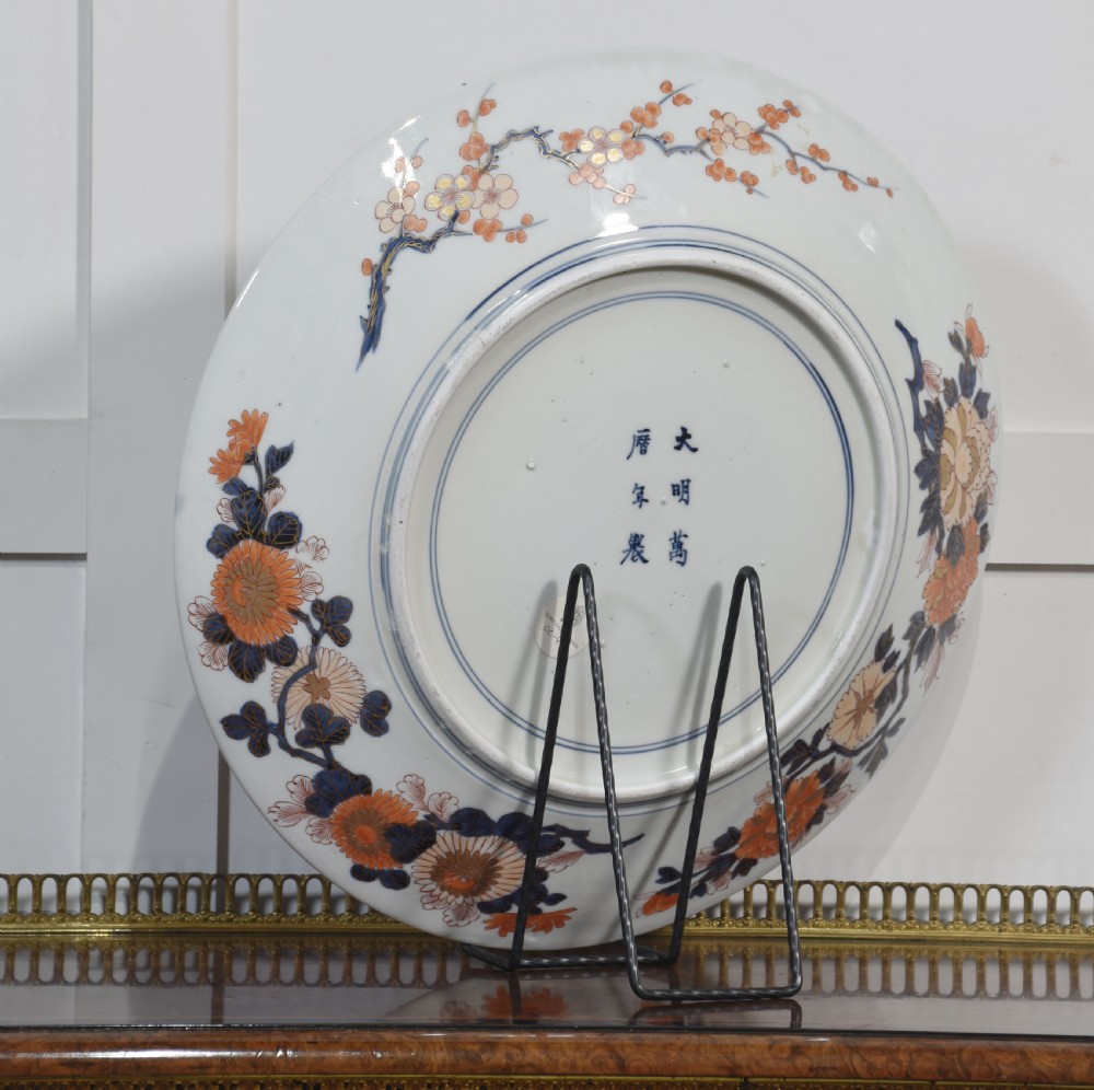 A circular Japanese Imari porcelain charger decorated with a blue and gold carp leaping up a waterfall amidst pine trees and geometric border motifs. View VIII