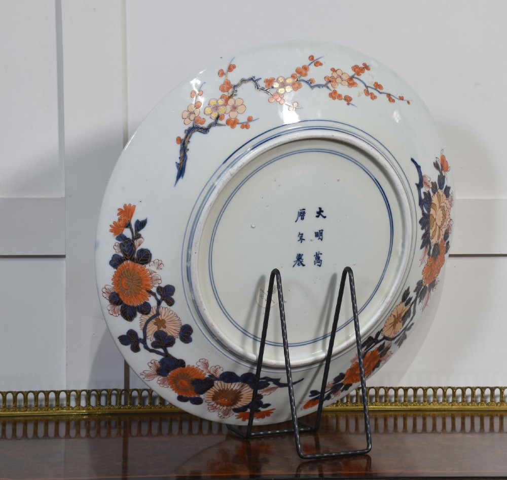 A circular Japanese Imari porcelain charger decorated with a blue and gold carp leaping up a waterfall amidst pine trees and geometric border motifs. View IX