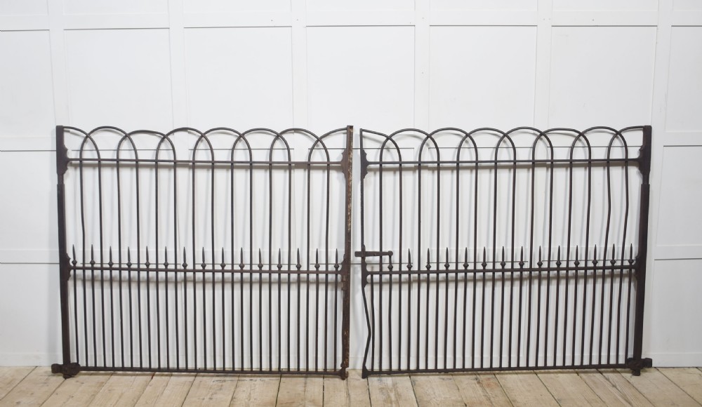 A pair of 19th-century wrought and cast iron gates featuring arched hoop tops, vertical pales, and central spearhead finials.