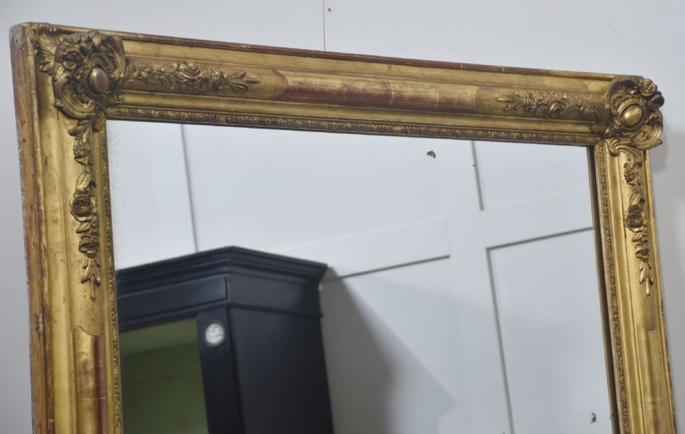 A large rectangular 19th-century wall mirror with a carved giltwood frame featuring ornate floral corner spandrels and moulded edges. View II