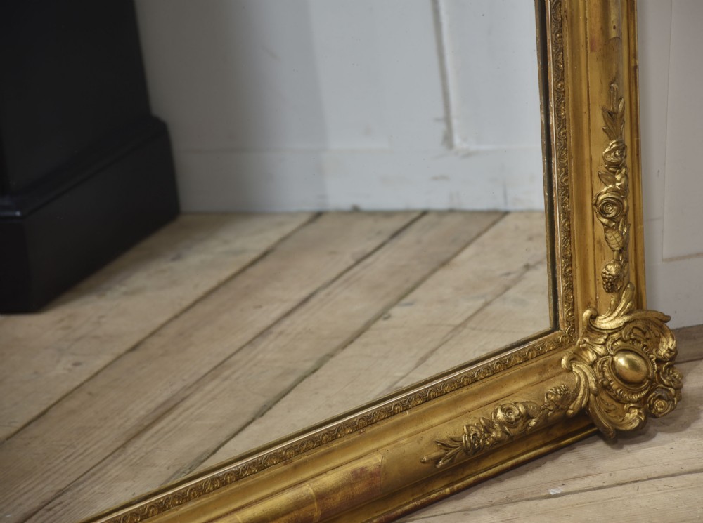 A large rectangular 19th-century wall mirror with a carved giltwood frame featuring ornate floral corner spandrels and moulded edges. View VIII