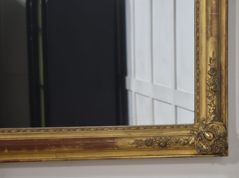 A large rectangular 19th-century wall mirror with a carved giltwood frame featuring ornate floral corner spandrels and moulded edges. View IX