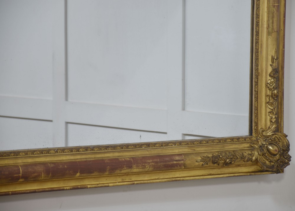 A large rectangular 19th-century wall mirror with a carved giltwood frame featuring ornate floral corner spandrels and moulded edges. View XIV