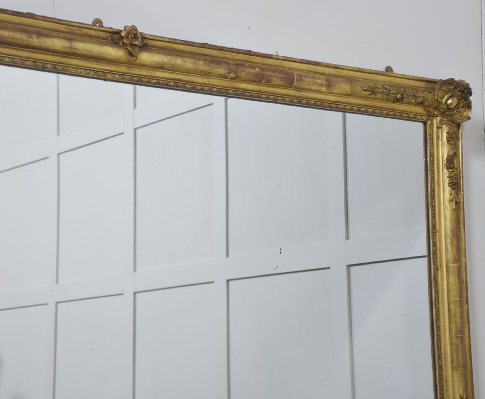 A large rectangular 19th-century wall mirror with a carved giltwood frame featuring ornate floral corner spandrels and moulded edges. View XV