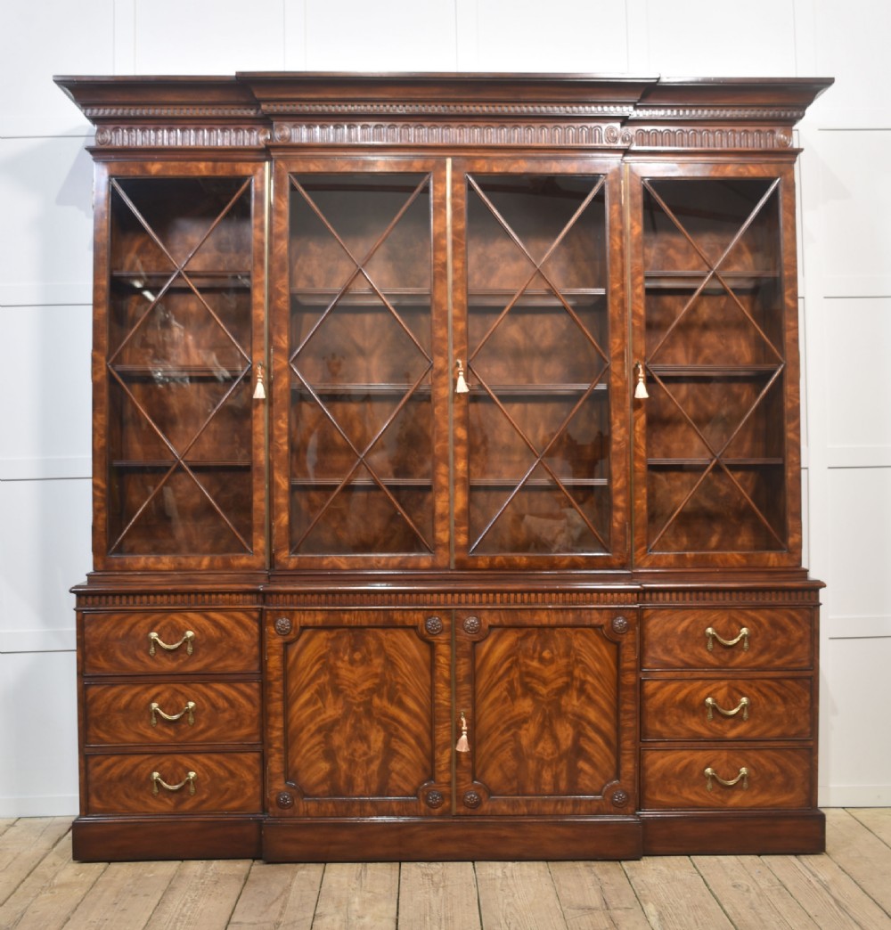 A large George III style mahogany breakfront library bookcase featuring glazed upper doors with astragal bars and a lower base with drawers and panelled cupboards.