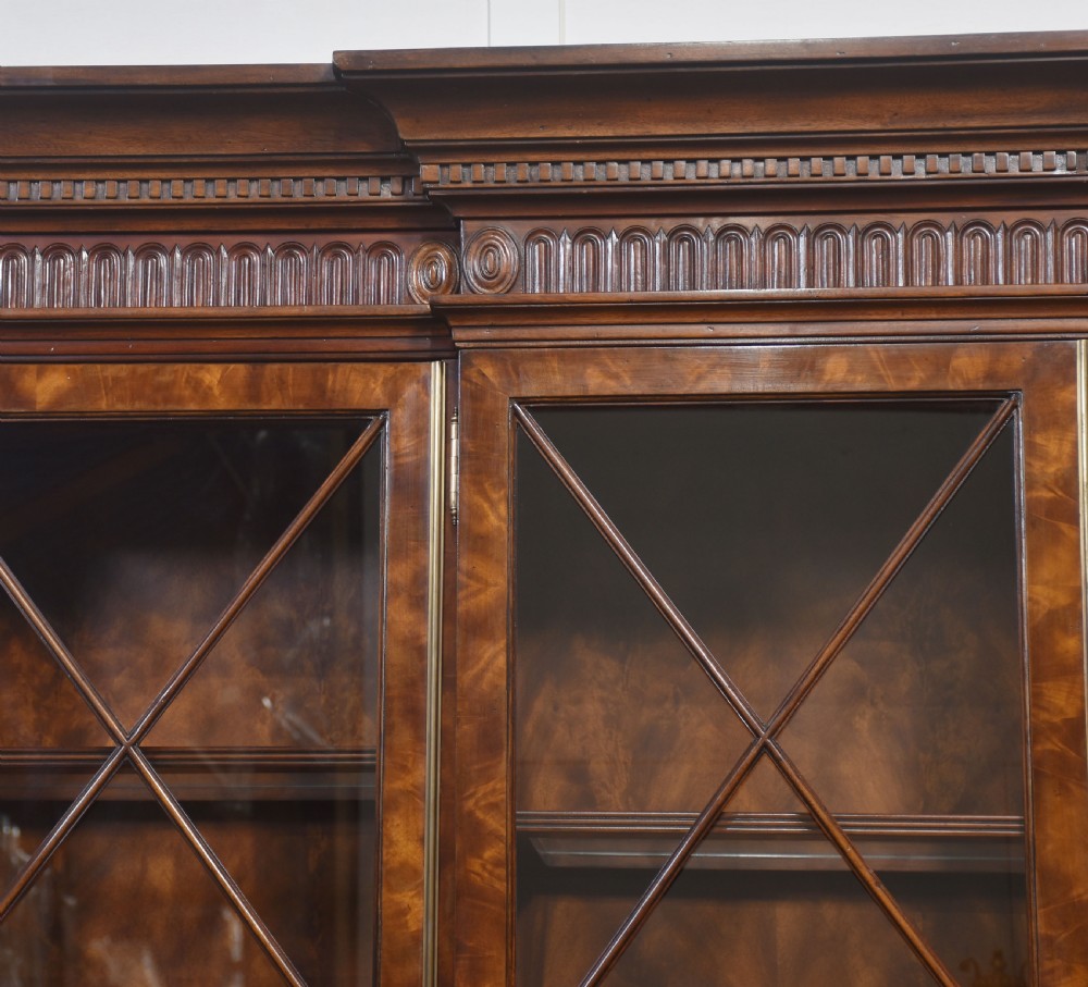 A large George III style mahogany breakfront library bookcase featuring glazed upper doors with astragal bars and a lower base with drawers and panelled cupboards. View XII