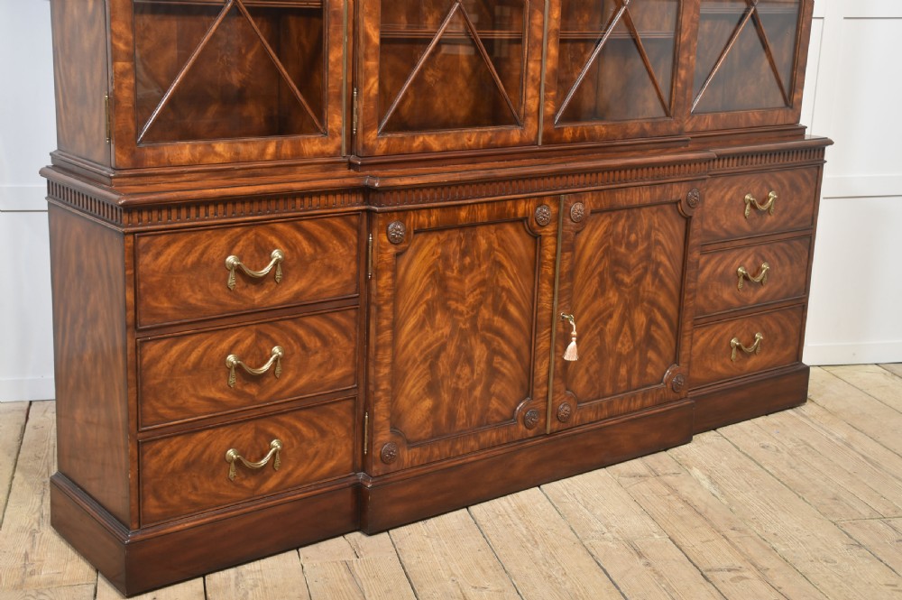 A large George III style mahogany breakfront library bookcase featuring glazed upper doors with astragal bars and a lower base with drawers and panelled cupboards. View XVI