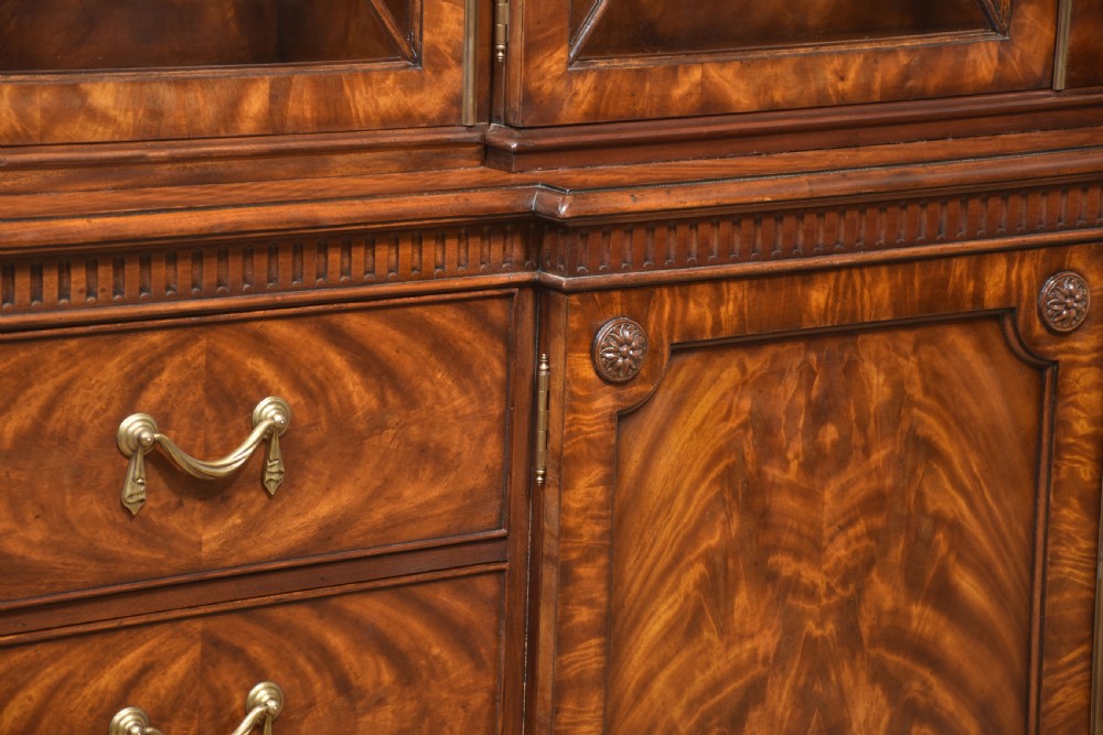A large George III style mahogany breakfront library bookcase featuring glazed upper doors with astragal bars and a lower base with drawers and panelled cupboards. View XVII