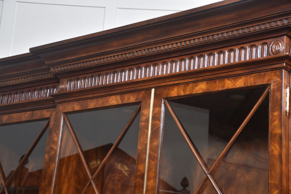 A large George III style mahogany breakfront library bookcase featuring glazed upper doors with astragal bars and a lower base with drawers and panelled cupboards. View XXI