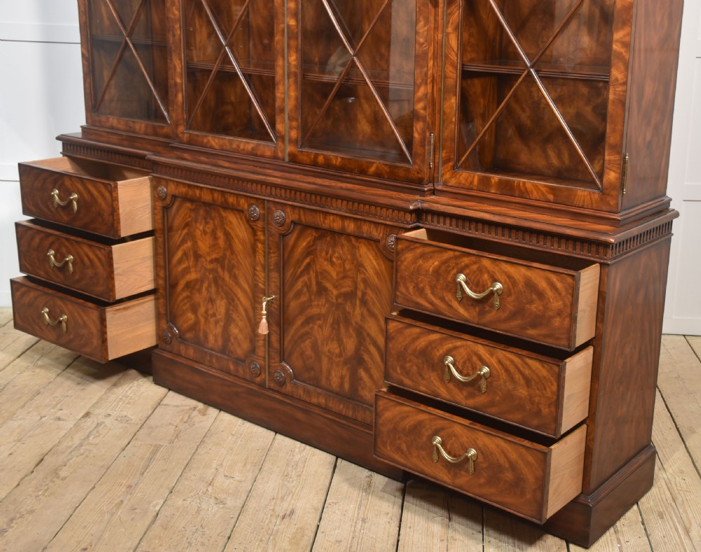 A large George III style mahogany breakfront library bookcase featuring glazed upper doors with astragal bars and a lower base with drawers and panelled cupboards. View XXIII