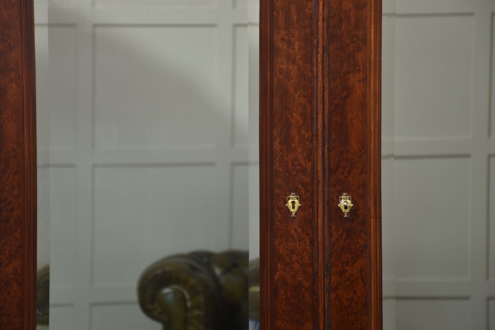 An Empire style mahogany wardrobe featuring twin mirrored doors, a classical pediment cornice, brass lion-ring drawer pulls, and gilt bronze mounts. View II