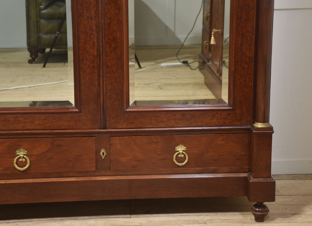 An Empire style mahogany wardrobe featuring twin mirrored doors, a classical pediment cornice, brass lion-ring drawer pulls, and gilt bronze mounts. View VIII