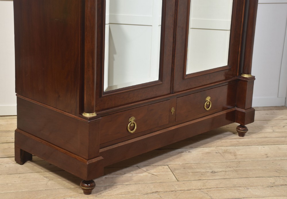 An Empire style mahogany wardrobe featuring twin mirrored doors, a classical pediment cornice, brass lion-ring drawer pulls, and gilt bronze mounts. View XII