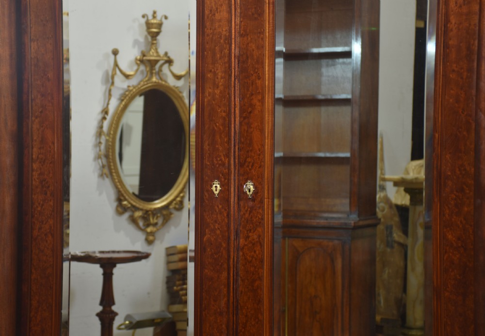 An Empire style mahogany wardrobe featuring twin mirrored doors, a classical pediment cornice, brass lion-ring drawer pulls, and gilt bronze mounts. View XVIII