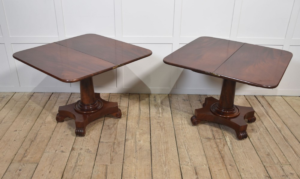 A pair of Regency mahogany fold-top tea tables resting on central cylindrical pedestals with quadruped scroll-foot bases. View XV