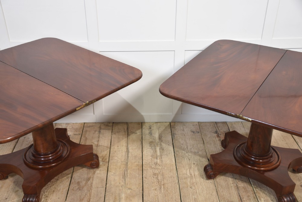 A pair of Regency mahogany fold-top tea tables resting on central cylindrical pedestals with quadruped scroll-foot bases. View XVI