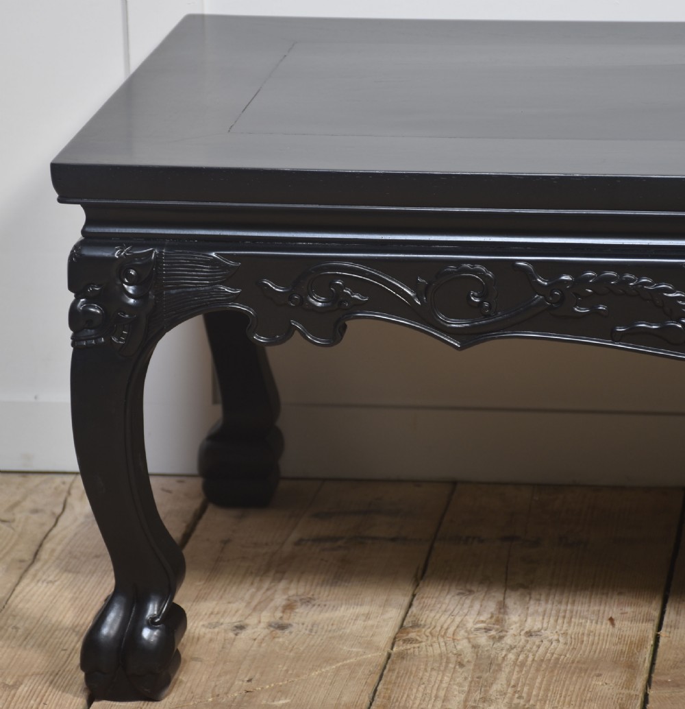 A low rectangular ebonised black wood coffee table featuring intricately carved aprons and shaped cabriole legs. View II