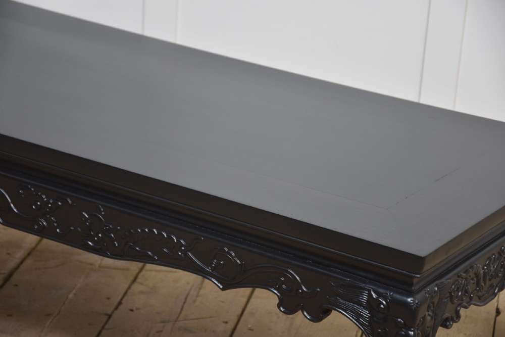A low rectangular ebonised black wood coffee table featuring intricately carved aprons and shaped cabriole legs. View VI