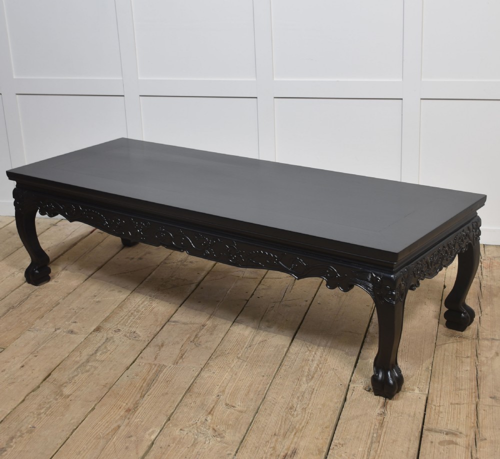 A low rectangular ebonised black wood coffee table featuring intricately carved aprons and shaped cabriole legs. View VII