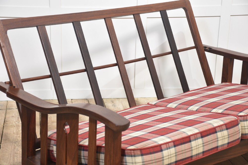 An Arts and Crafts solid walnut two-seater settee with red and cream tartan plaid upholstered cushions. View V