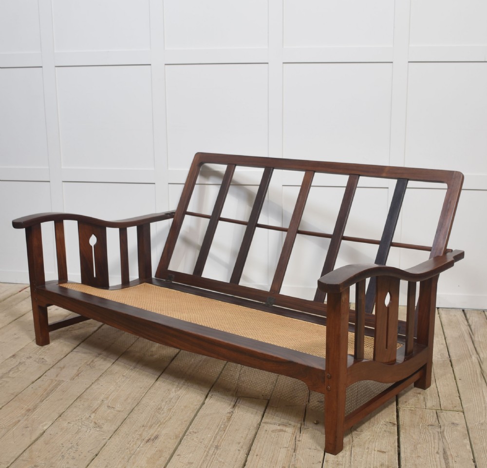 An Arts and Crafts solid walnut two-seater settee with red and cream tartan plaid upholstered cushions. View VI