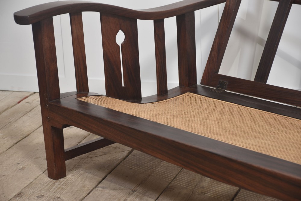 An Arts and Crafts solid walnut two-seater settee with red and cream tartan plaid upholstered cushions. View VII