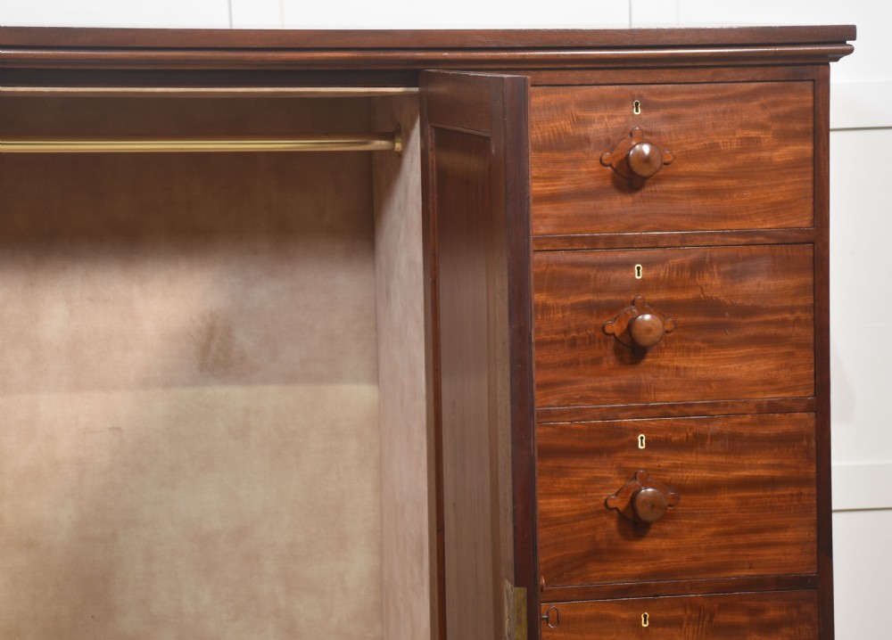 A 19th-century low mahogany linen press with a central double-door cupboard flanked by ten drawers with turned wooden knobs. View III