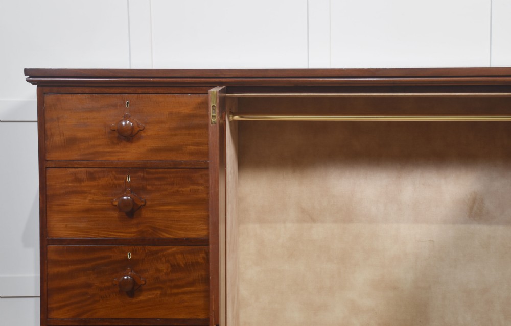 A 19th-century low mahogany linen press with a central double-door cupboard flanked by ten drawers with turned wooden knobs. View V