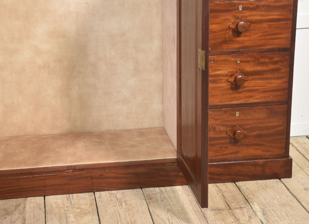 A 19th-century low mahogany linen press with a central double-door cupboard flanked by ten drawers with turned wooden knobs. View VII