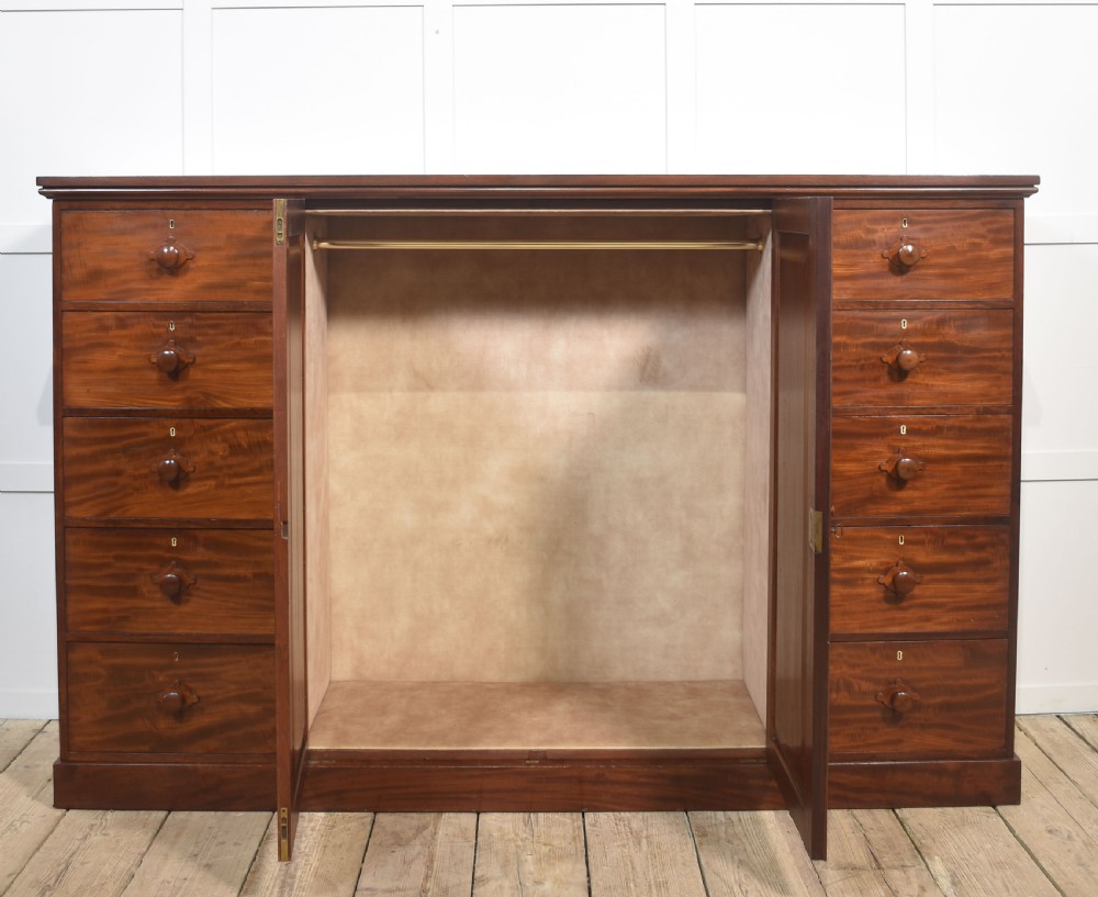 A 19th-century low mahogany linen press with a central double-door cupboard flanked by ten drawers with turned wooden knobs. View VIII