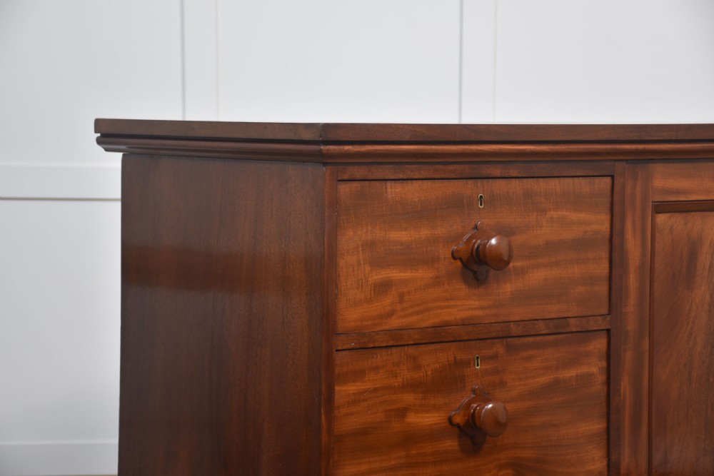 A 19th-century low mahogany linen press with a central double-door cupboard flanked by ten drawers with turned wooden knobs. View IX