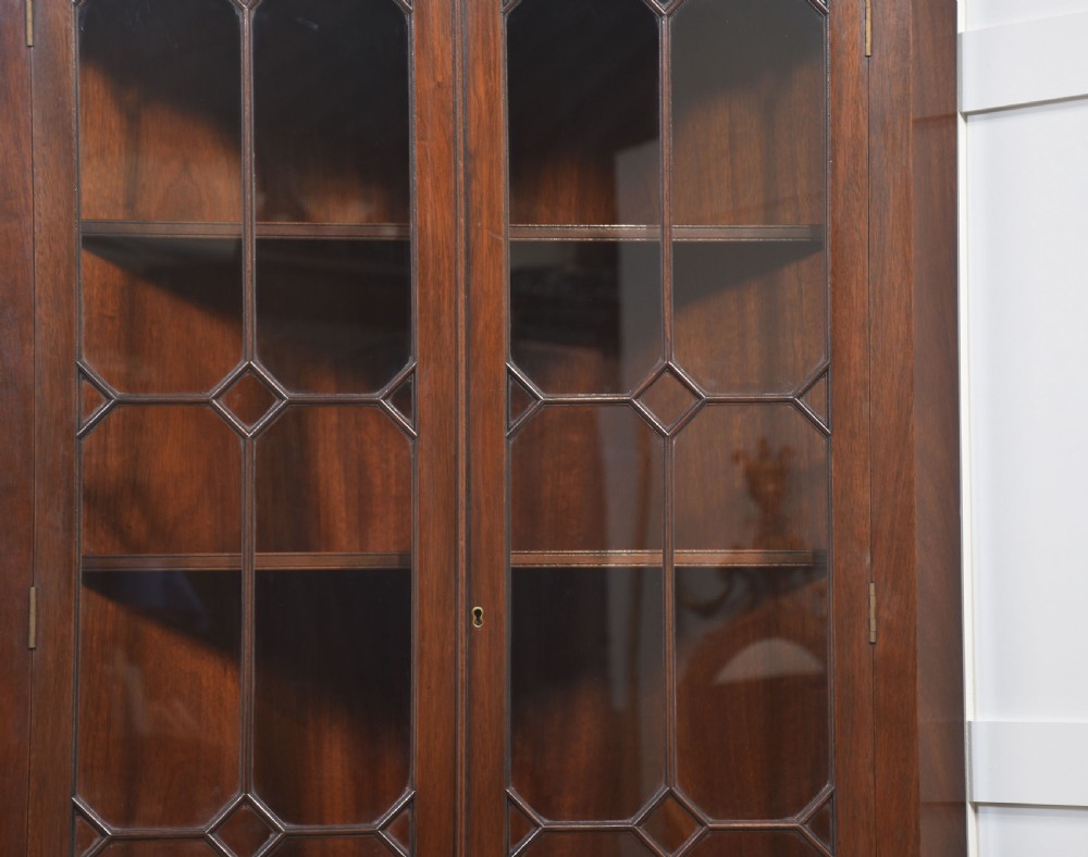 A tall two-tier mahogany corner cabinet featuring astragal glazed upper doors and flame mahogany veneered lower doors. View VII