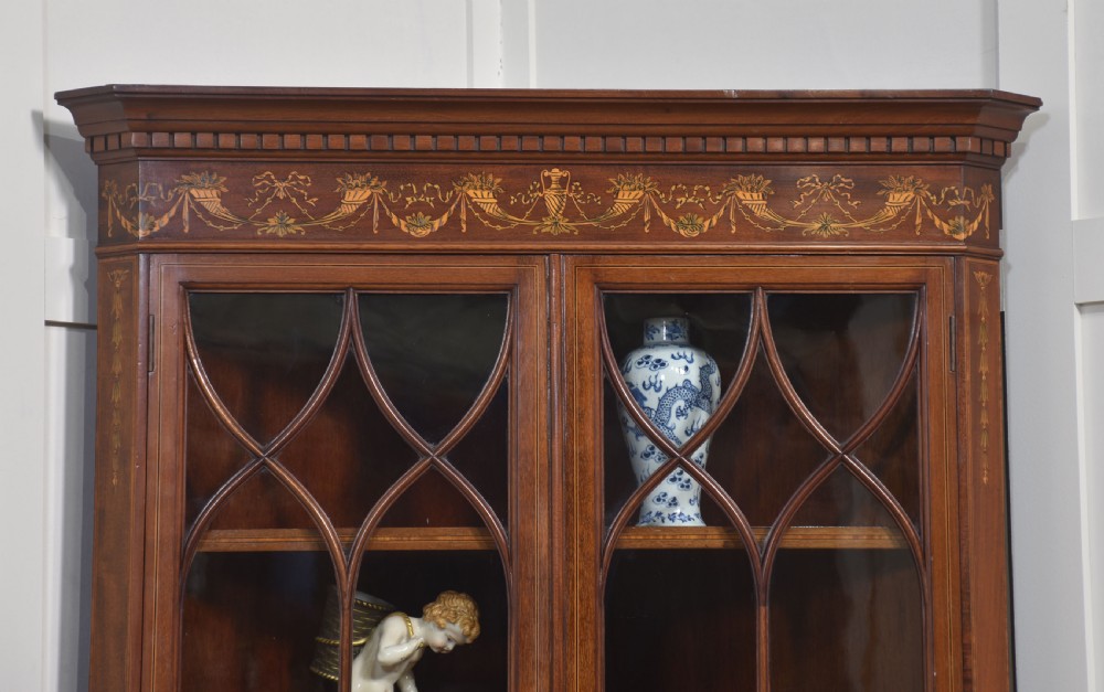 A tall mahogany corner cabinet featuring glazed upper doors with astragal tracery and lower doors ornamented with floral marquetry inlay. View VI