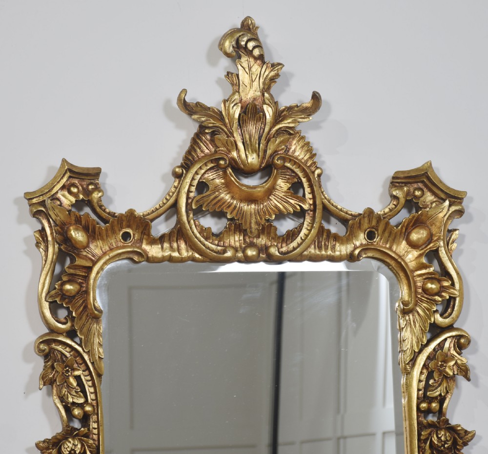 A matching pair of rectangular wall mirrors framed in intricately carved gold giltwood with elaborate floral cresting and scroll motifs. View XIII