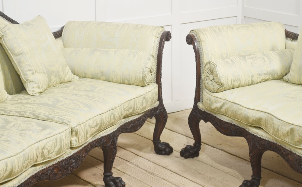A pair of carved dark mahogany Chippendale revival settees upholstered in light sage patterned fabric with ball-and-claw feet. View V