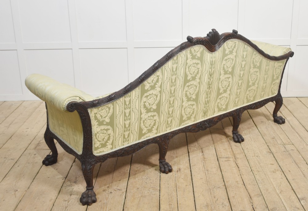 A pair of carved dark mahogany Chippendale revival settees upholstered in light sage patterned fabric with ball-and-claw feet. View XIX