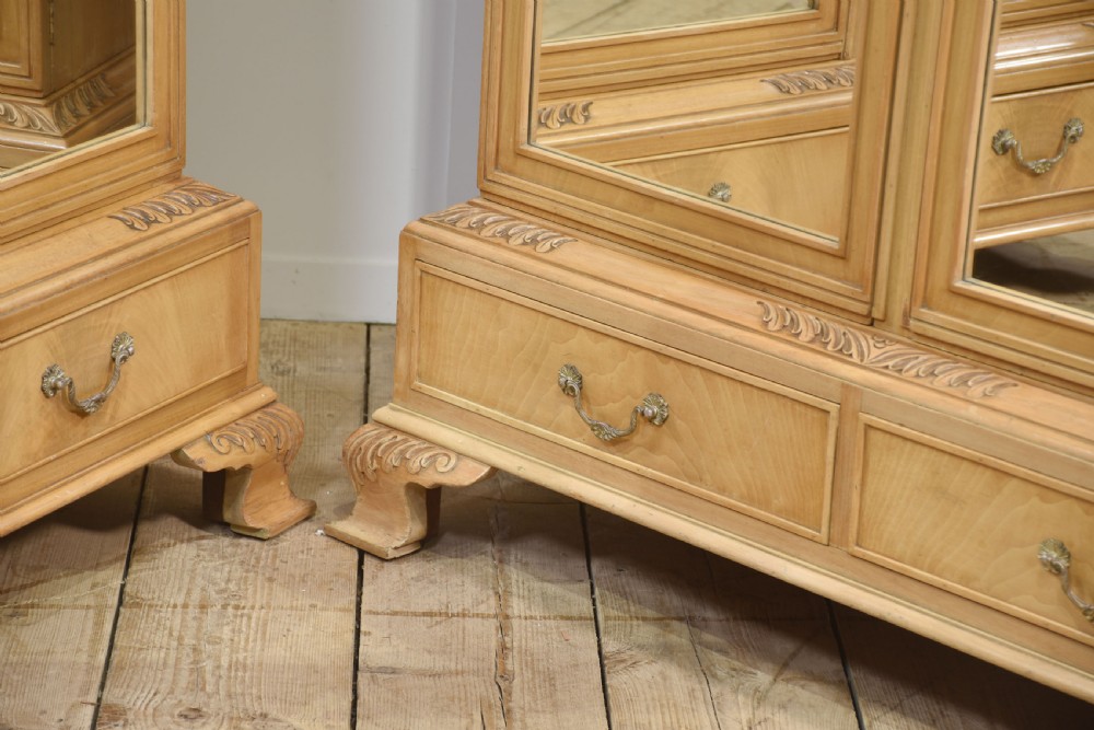 A near pair of tall light walnut wardrobes featuring twin arched mirrored doors, rope-twist carved borders, shell motifs, and two base drawers on carved feet. View III